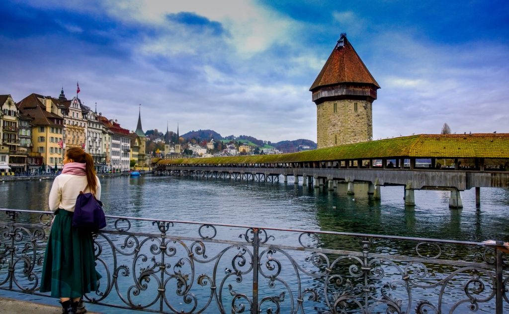 woman standing against handrails beside body of water